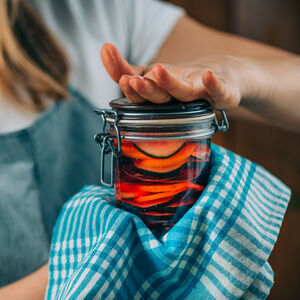 woman holding a glass with fermented vegetables